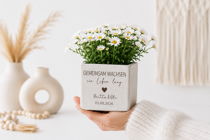 Personalisierter Blumentopf mit Namen und Datum als kleine Aufmerksamkeit für Hochzeit, Valentinstag oder Jubiläum. Stilvolle Betonoptik mit liebevoller Gravur und modernen weißen Margeriten.