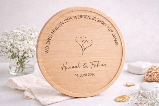 Graviertes Servierbrett zur Hochzeit mit zwei Herzen Motiv und individueller Namensgravur, dekoriert mit Eheringen und Blumen – personalisiertes Geschenk zur Trauung.
