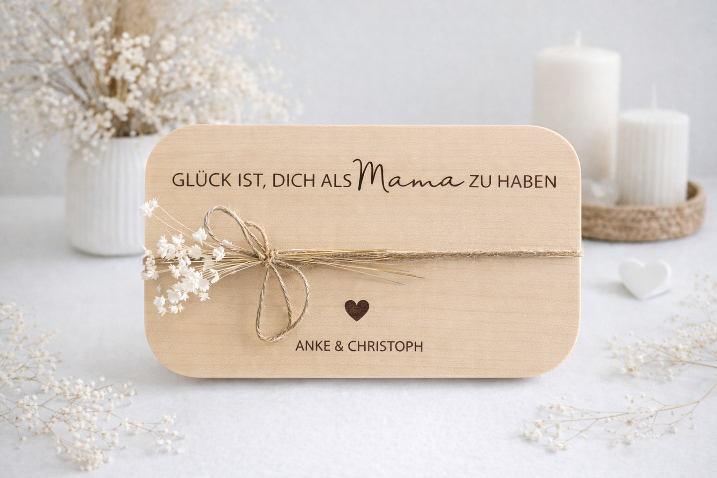 Hochwertiges Frühstücksbrett aus Holz mit eingravierter Botschaft „Glück ist, dich als Mama zu haben“, personalisiert mit zwei Namen und Herzsymbol, stilvoll inszeniert mit Kerzen und zarter Deko – emotionales Geschenk für Mama von Kindern.