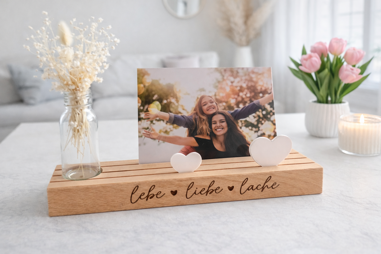 Kartenhalter personalisiert aus Holz mit Gravur „lebe liebe lache“ und weißen Herz-Elementen, dekorative Bilderleiste Holz mit Foto von zwei Freundinnen in heller moderner Wohnszene, stilvoller Kartenständer für Postkarten und Erinnerungsfotos, Geschenk beste Freundin als kleine Aufmerksamkeit, hochwertiges Geschenk aus Holz handgemacht in Baden-Württemberg von MH Dekodesign – Kleine Geschenkewelt
