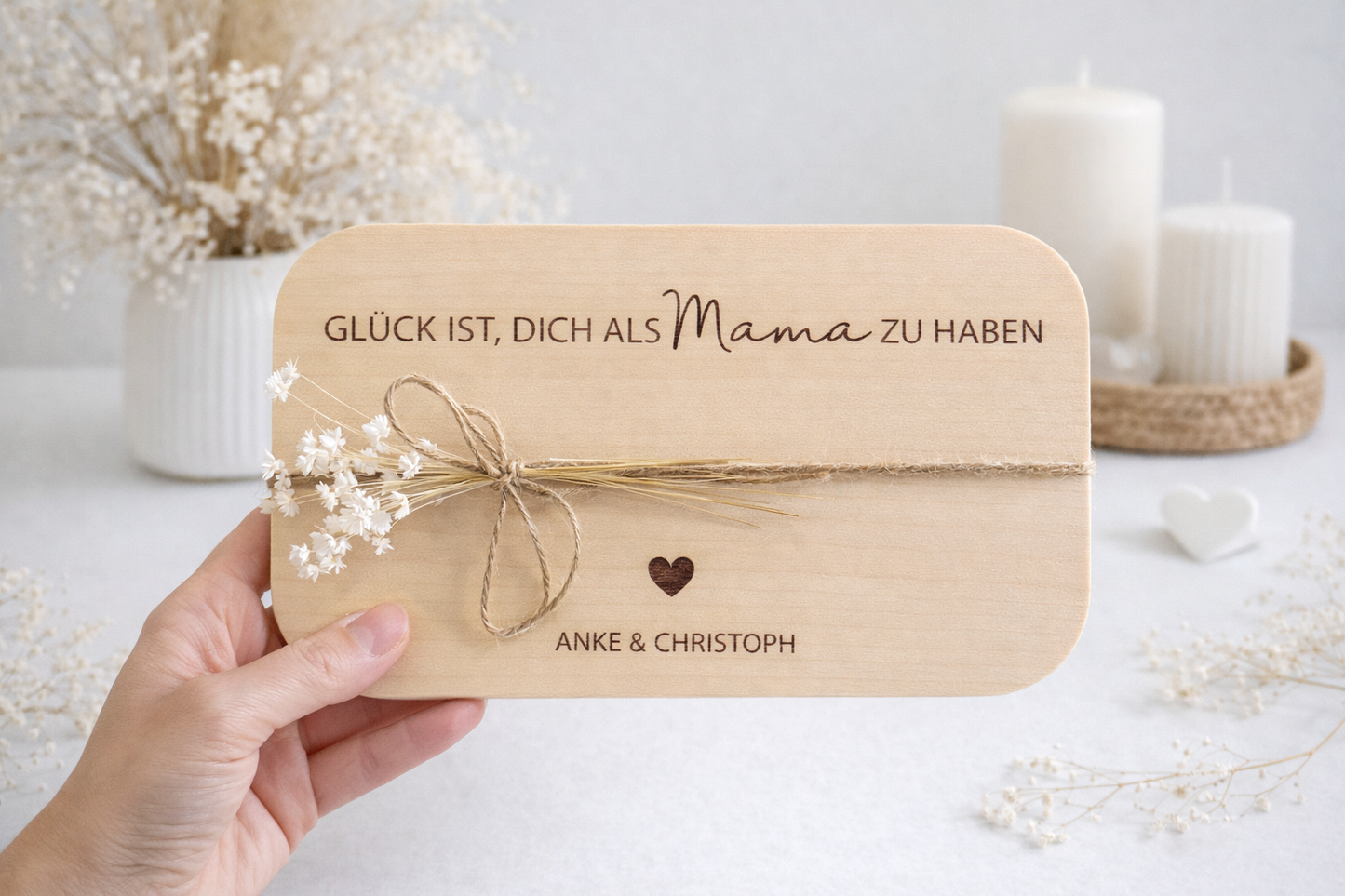 Personalisiertes Holzbrett aus hellem Holz mit Gravur „Glück ist, dich als Mama zu haben“ und Namen Anke & Christoph, dekoriert mit Juteband und weißen Trockenblumen auf modernem hellweißen Hintergrund – liebevolles Geschenk für Mama zum Muttertag, Geburtstag oder Weihnachten.
