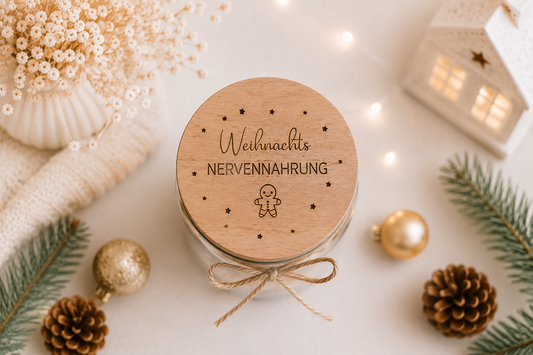 Weihnachtliches Vorratsglas mit graviertem Holzdeckel und Spruch „Weihnachts Nervennahrung“, dekoriert mit Lebkuchenmann und Sternen.
