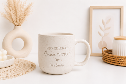 Personalisierte Steingut Tasse in Beige mit Gravur „Glück ist, dich als Mama zu haben – Deine Jennifer“ als emotionales Muttertagsgeschenk auf einem hellen Tisch mit Boho-Dekoration.